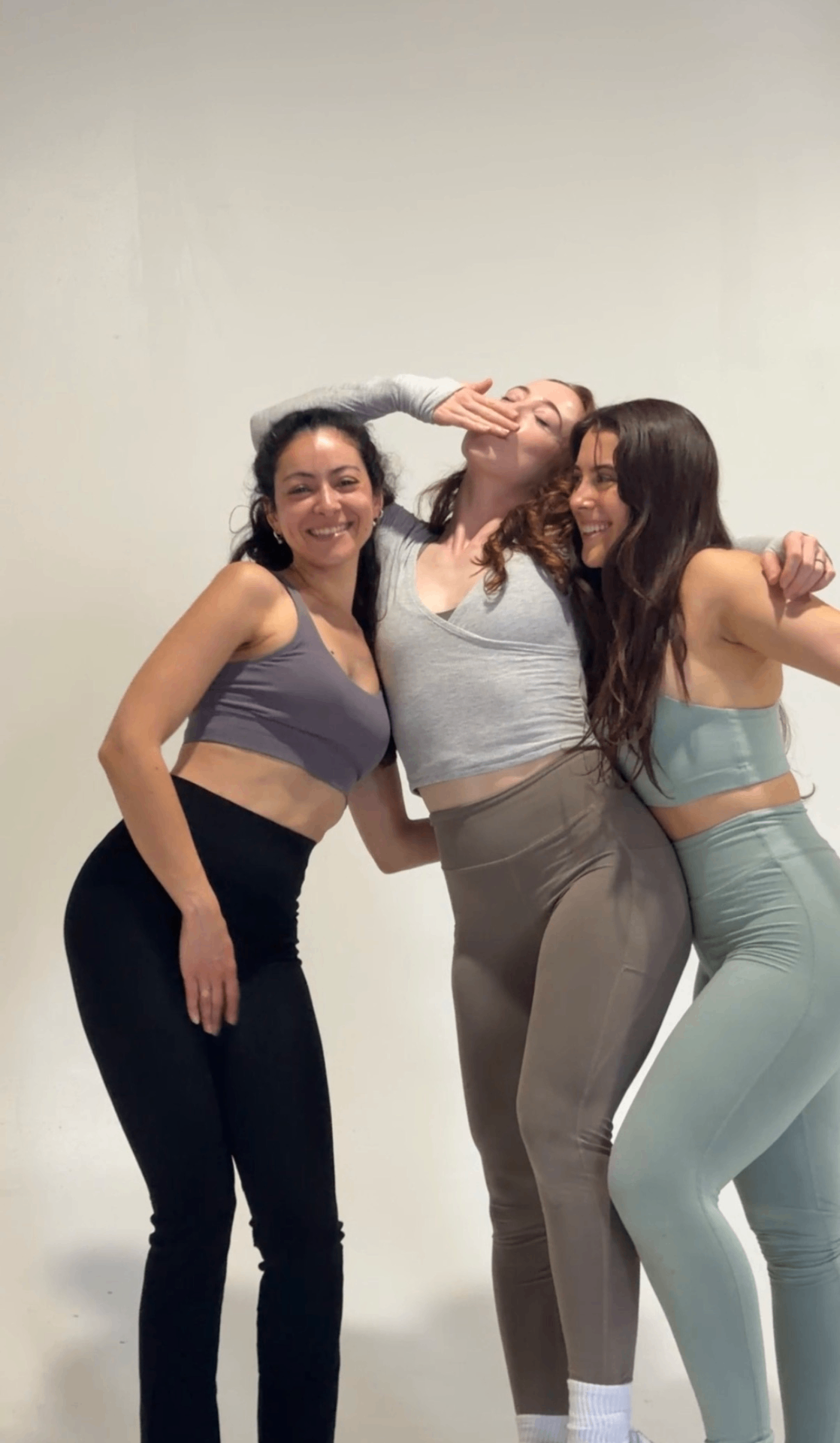 Three friends laughing and leaning into each other after class.